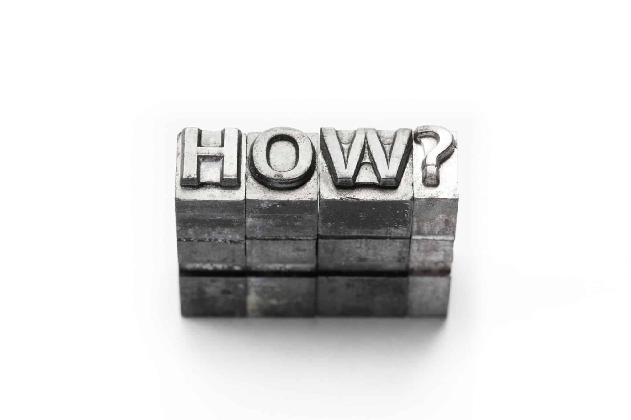 Metal bricks spelling out HOW? on a white background
